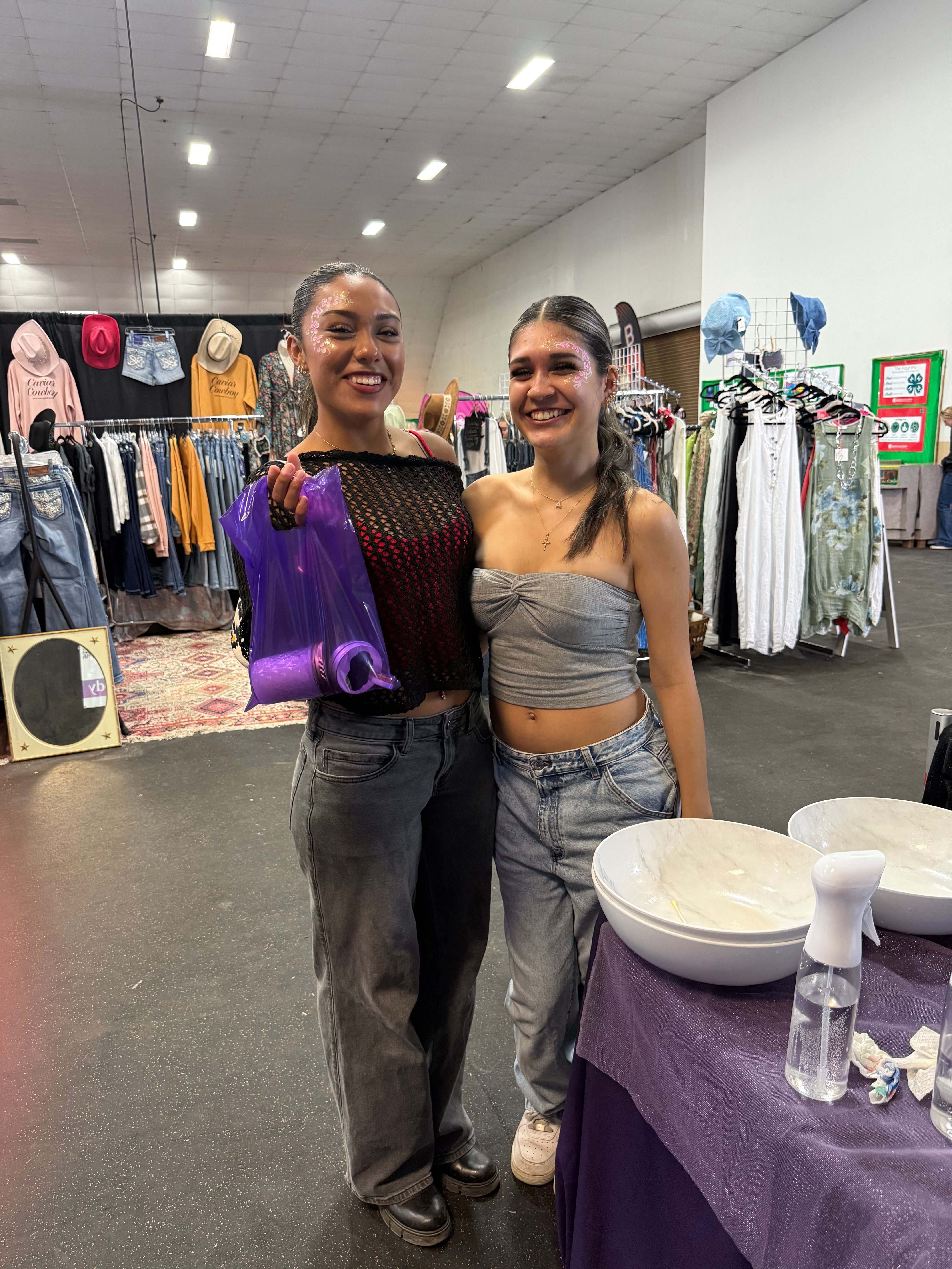 Two customers with festival face glitter at the Embrace Your Body booth.